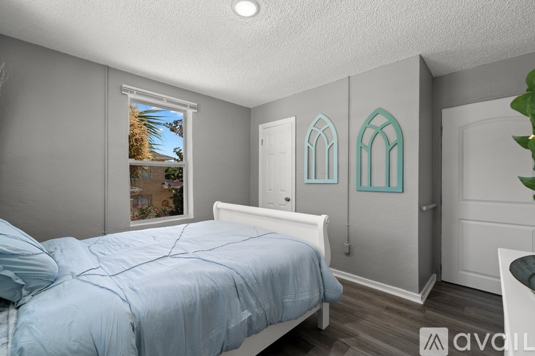 A bedroom with a bed, a window, and a door.