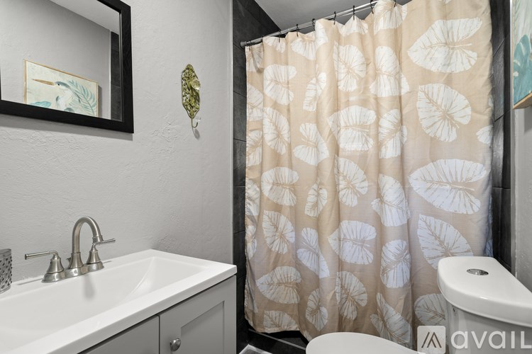 A bathroom with a sink, mirror, and shower curtain.