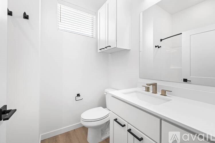 A white bathroom with a toilet, sink, and mirror.
