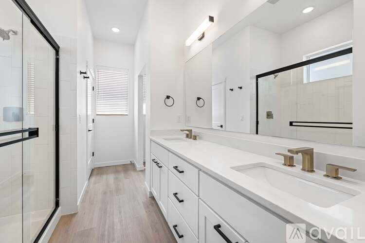A modern bathroom with a walk-in shower and double sinks.