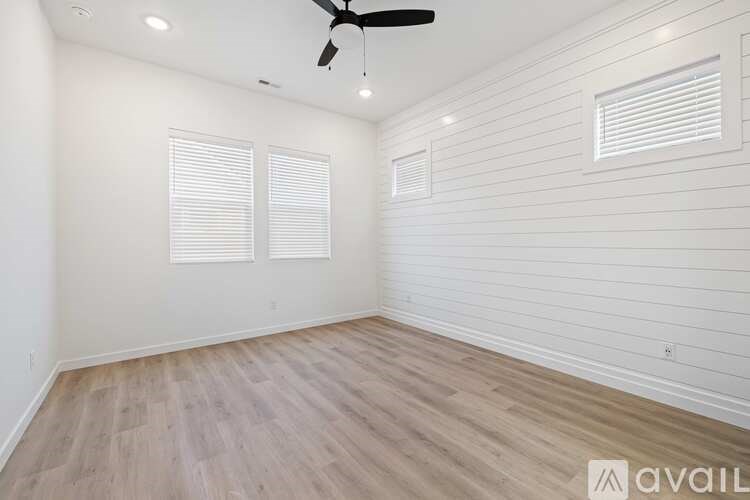 A room with a ceiling fan and two windows.