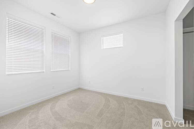 A room with a carpeted floor and a window with blinds.