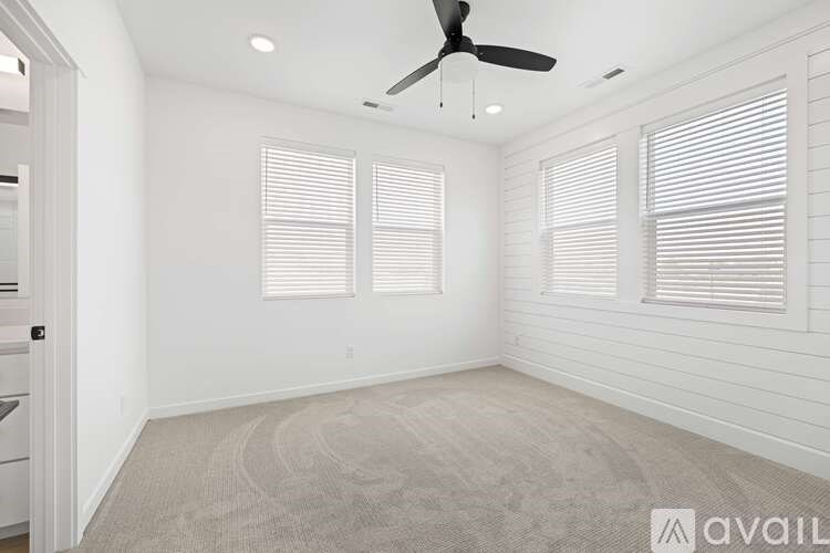 A room with a ceiling fan and two windows with blinds.