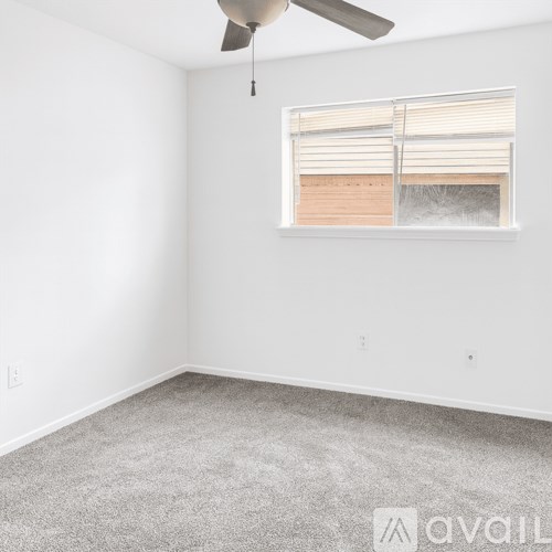 A room with a ceiling fan and a window with blinds.
