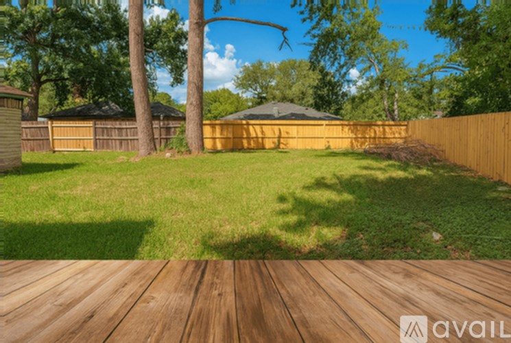 A wooden deck leads to a backyard with a fence, trees, and a shed.