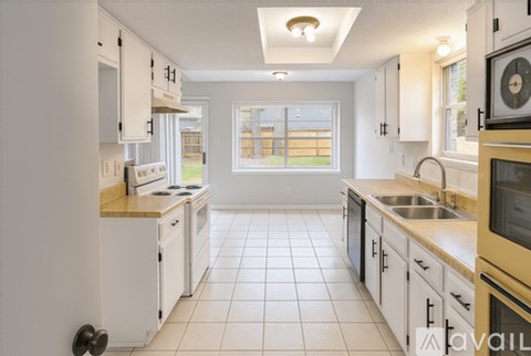 A kitchen with white cabinets and a tiled floor.