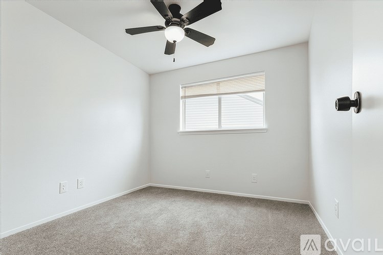 A room with a ceiling fan and a window with blinds.