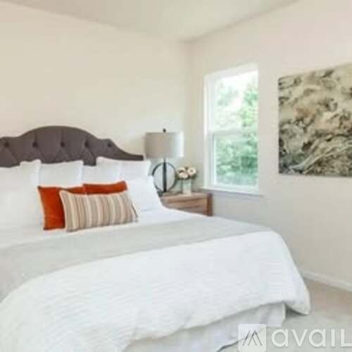 A bedroom with a large bed and a painting on the wall.