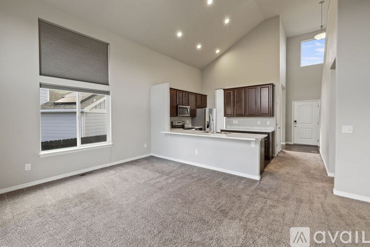A spacious living room with a kitchenette and a large window.