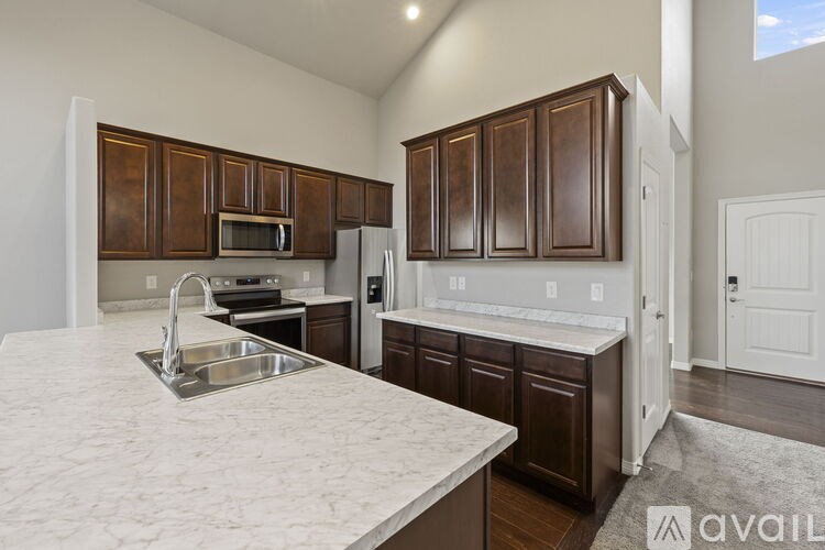 A kitchen with brown cabinets and a marble countertop.