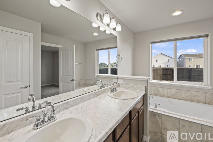 A bathroom with a large mirror, two sinks, and a tub.