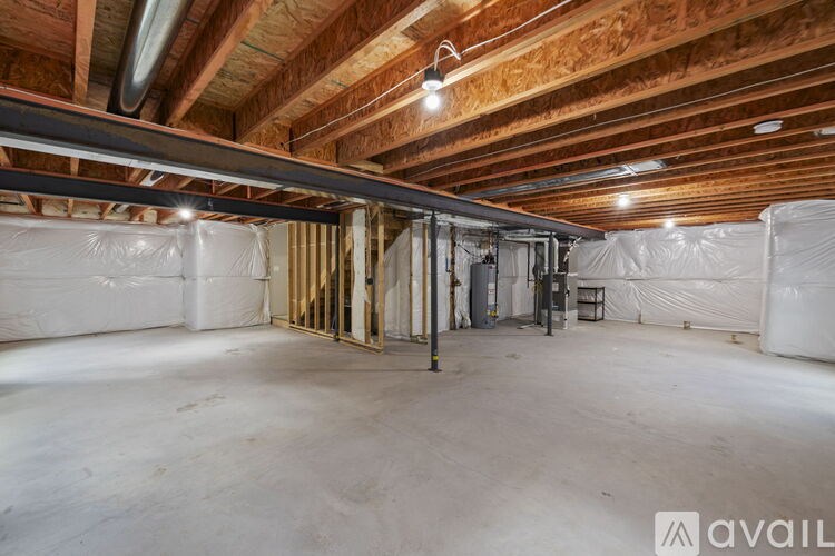 A spacious unfinished room with wooden beams on the ceiling and insulation on the walls.