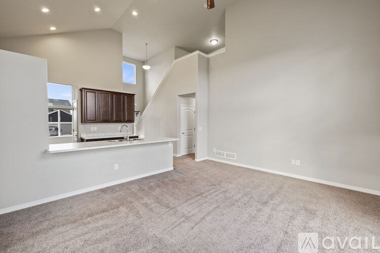 A spacious living room with a carpeted floor and a staircase leading to the upper level.