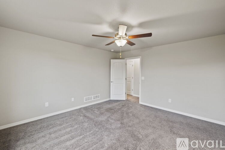 A room with a ceiling fan and carpeted floor.