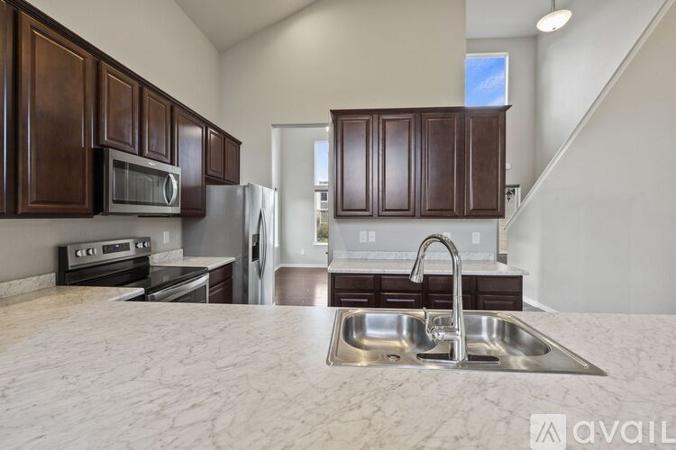 A kitchen with brown cabinets and a marble countertop.