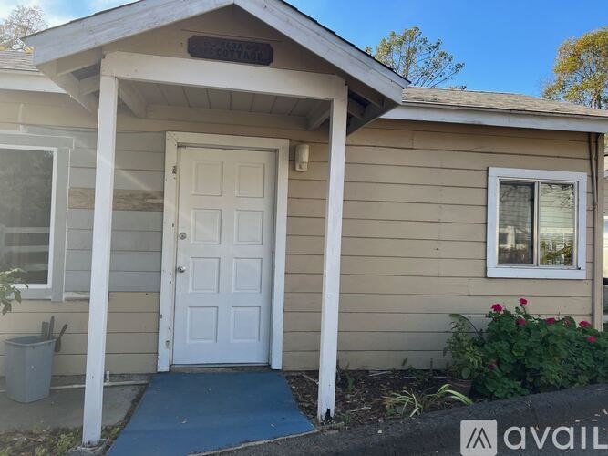 A small house with a white door and a blue mat in front.