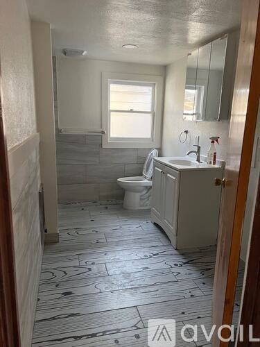 A bathroom with a toilet, sink, and mirror.