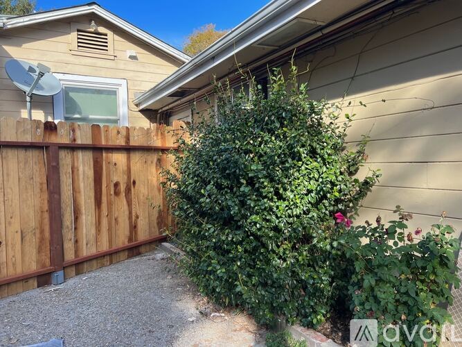 A house with a brown fence and green plants.
