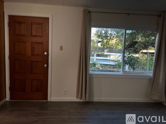 A room with a brown door and a window with curtains.