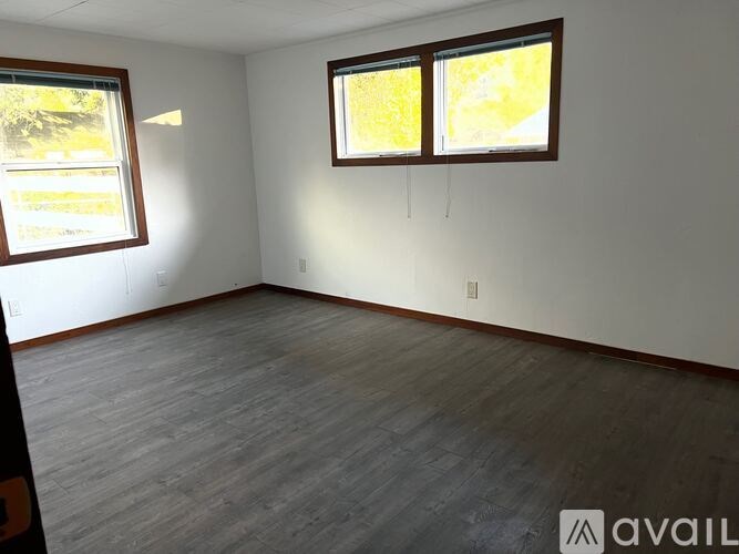 A room with two windows and wooden flooring.
