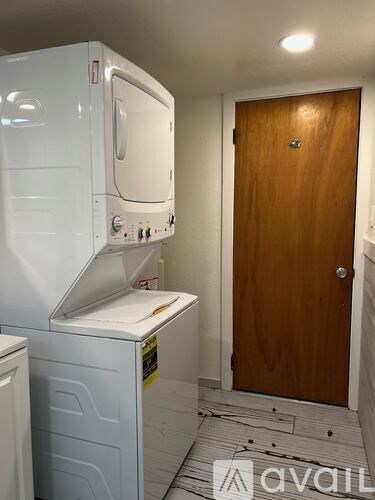 A white dishwasher and dryer stacked on top of each other in a small room.