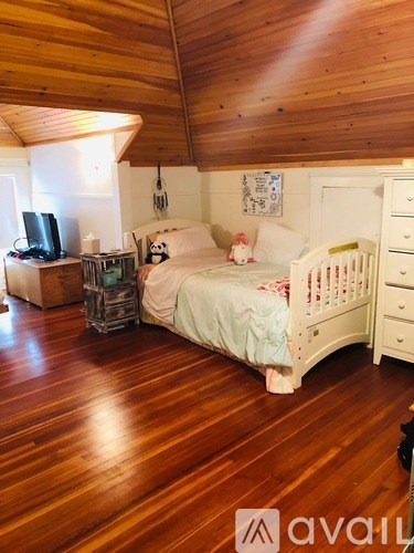 A baby's room with a white crib and wooden floors.