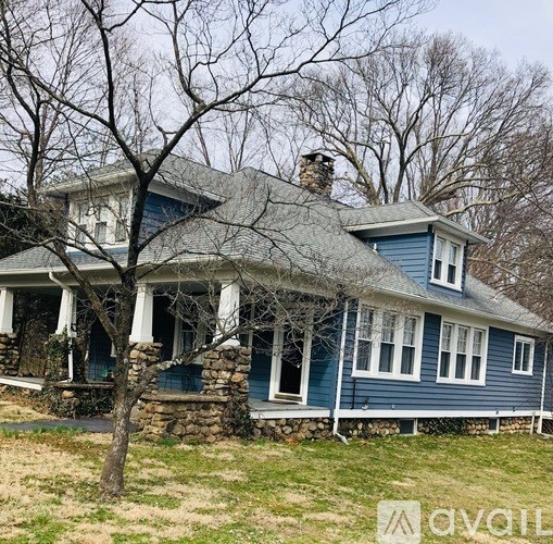 A blue house with a stone foundation and a thatched roof.