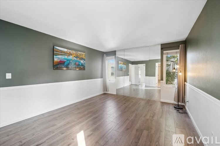 A spacious living room with wooden flooring and a flat-screen TV.
