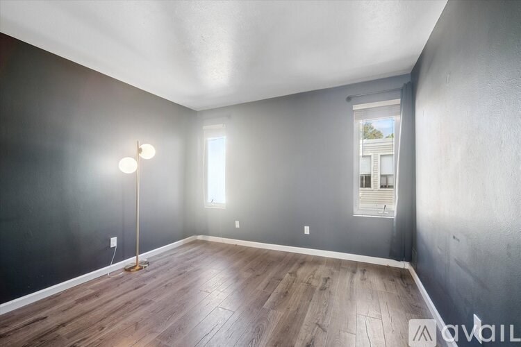 A room with a wooden floor and a window with blinds.