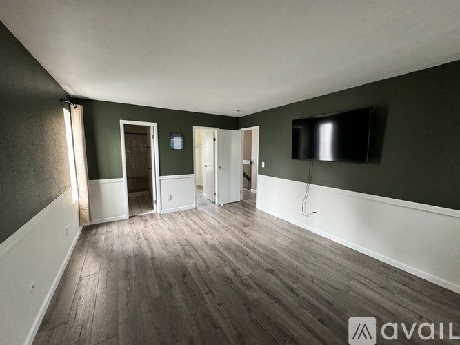 A room with a television on the wall and wooden flooring.