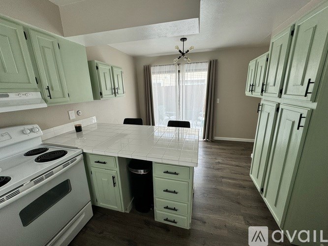 A kitchen with green cabinets and a white stove top oven.
