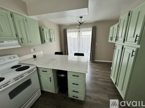A kitchen with green cabinets and a white stove top oven.