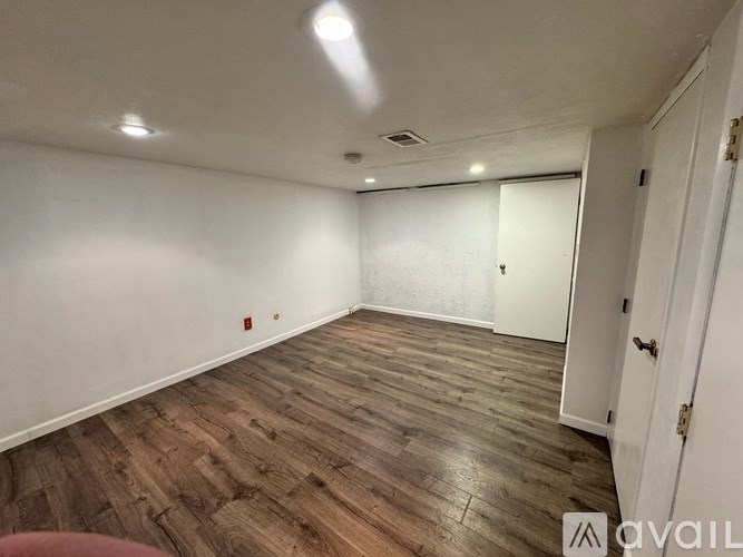 A room with wooden flooring and white walls.