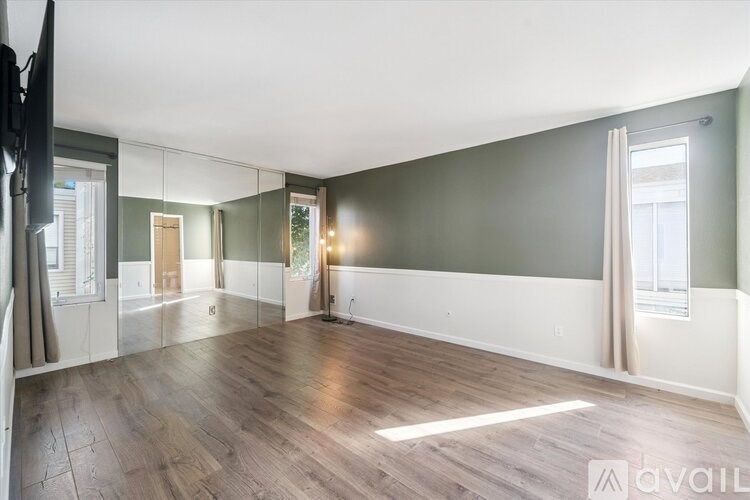 A spacious room with wooden flooring and a large mirror on the wall.