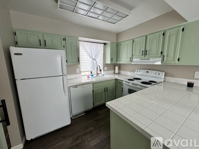 A kitchen with green cabinets and white appliances.