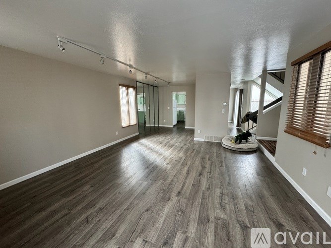 A spacious room with wooden flooring and a vacuum cleaner in the middle.