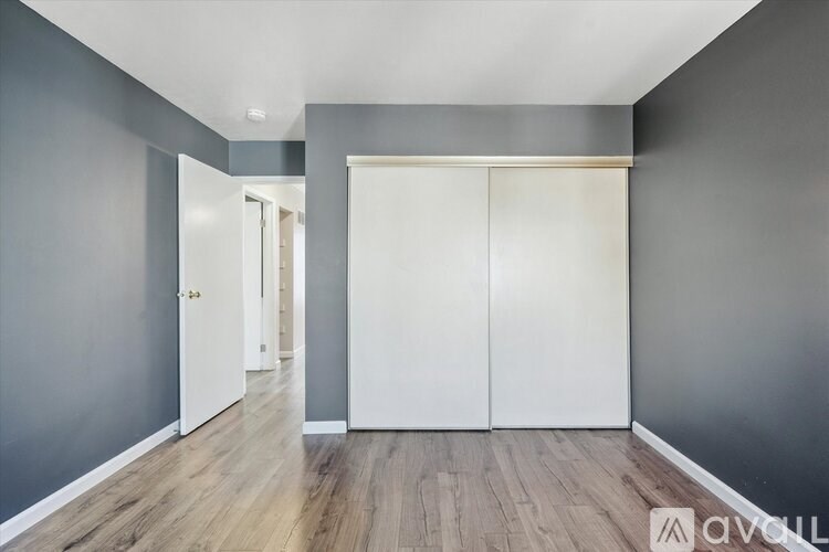 A white toilet with a white tank is in a bathroom with white walls.