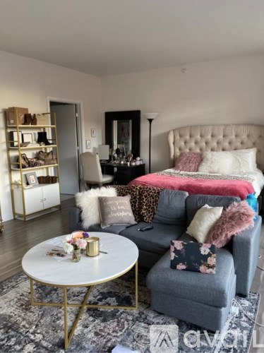A bedroom with a grey couch and a white bed.