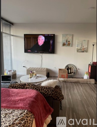 A living room with a leopard print couch and a television on the wall.