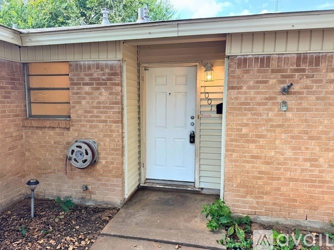 A white door is on the right side of a brick wall.