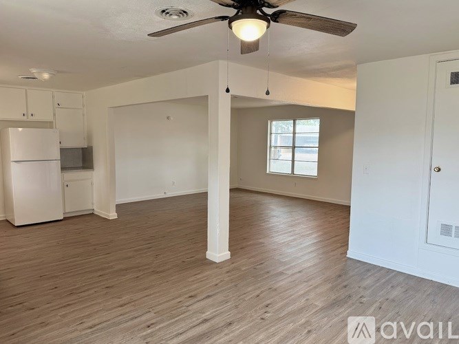 A spacious room with a ceiling fan and wooden flooring.