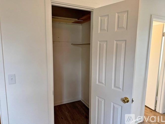 A white door with a gold handle is open to a small, empty room.