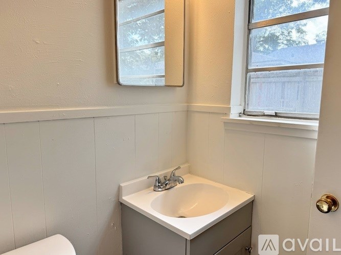 A small white sink in a cabinet under a mirror.
