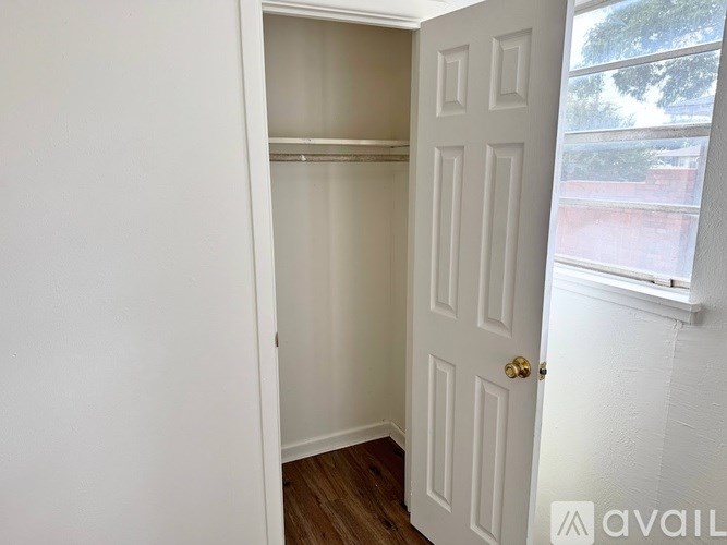 A white door with a gold handle is open to a room with a window.