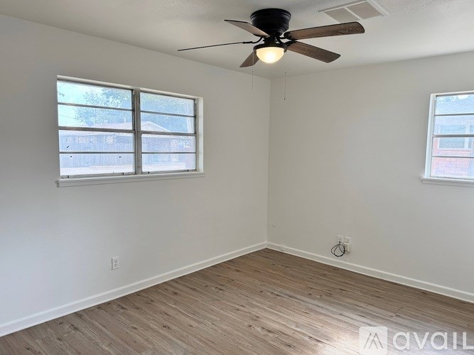 A room with a ceiling fan and two windows.
