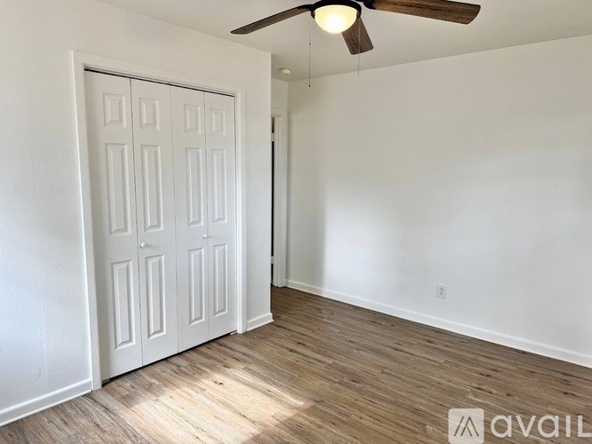 A room with a white door and a ceiling fan.
