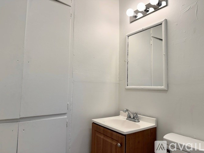 A bathroom with a sink, mirror, and light fixture.