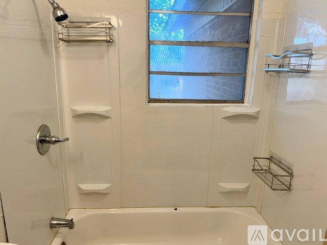 A white bathroom with a tub, shower, and a window.