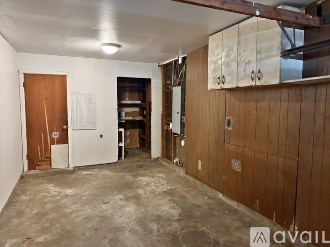 A room with a wooden door and a white door, both with a handle on the right side.
