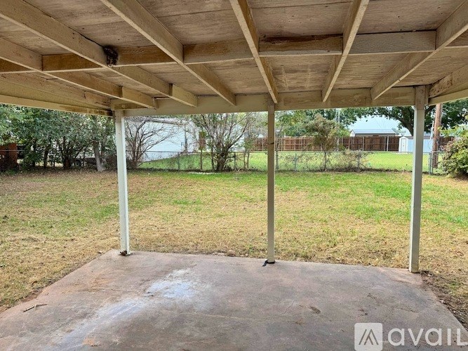 A covered patio area with a concrete floor and wooden ceiling.